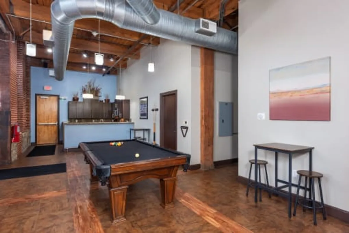 A lively communal space with a pool table, a stylish bar area, and expressive artwork, designed for socializing and relaxation. The atmosphere is casual and friendly, perfect for unwinding or connecting with others after a productive day.